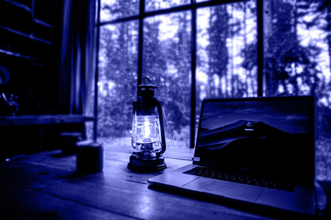 lantern sitting on table next to mac computer with blue tinted background
